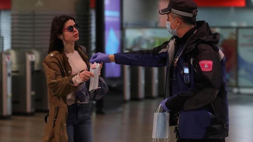 Un agent dona una mascareta a una viatgera del metro de Madrid