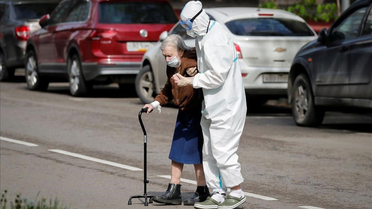 Personal sanitario de Moscú ayuda a una anciana a cruzar la calle