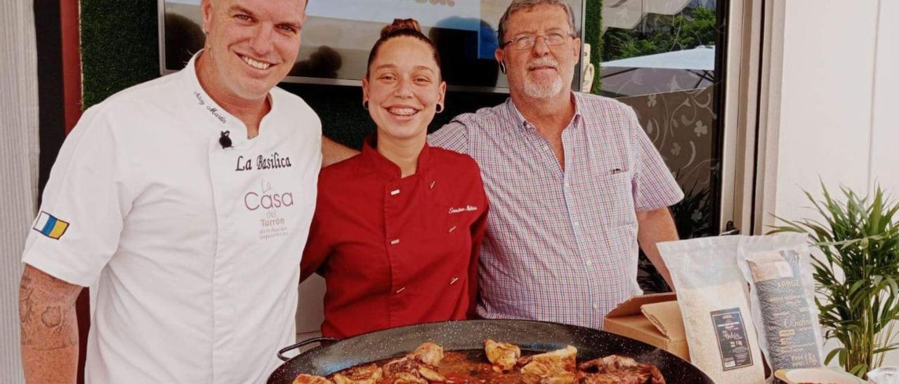 Aday Martín (i), junto a Sandra, jefa de cocina de La Basílica, y Pedro Pacheco, de La Casa del Turrón, con la paella Valenciana que llevará a concurso. | | E.D.