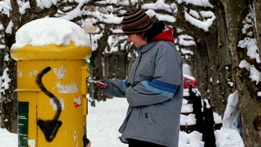 Una persona introduce una carta en un buzón de correos