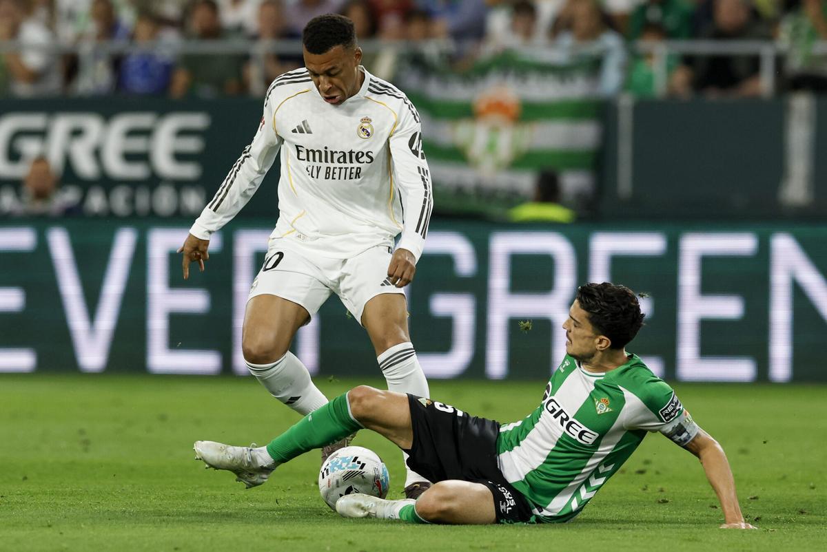 El delantero francés del Real Madrid, Kylian Mbappé (i), disputa el balón ante el defensa del Betis, Marc Bartra, durante el encuentro correspondiente a la jornada 32 de Laliga EA Sports que disputan este viernes Betis y Real Madrid en el estadio de La Cartuja, en Sevilla. EFE / Julio Muñoz
