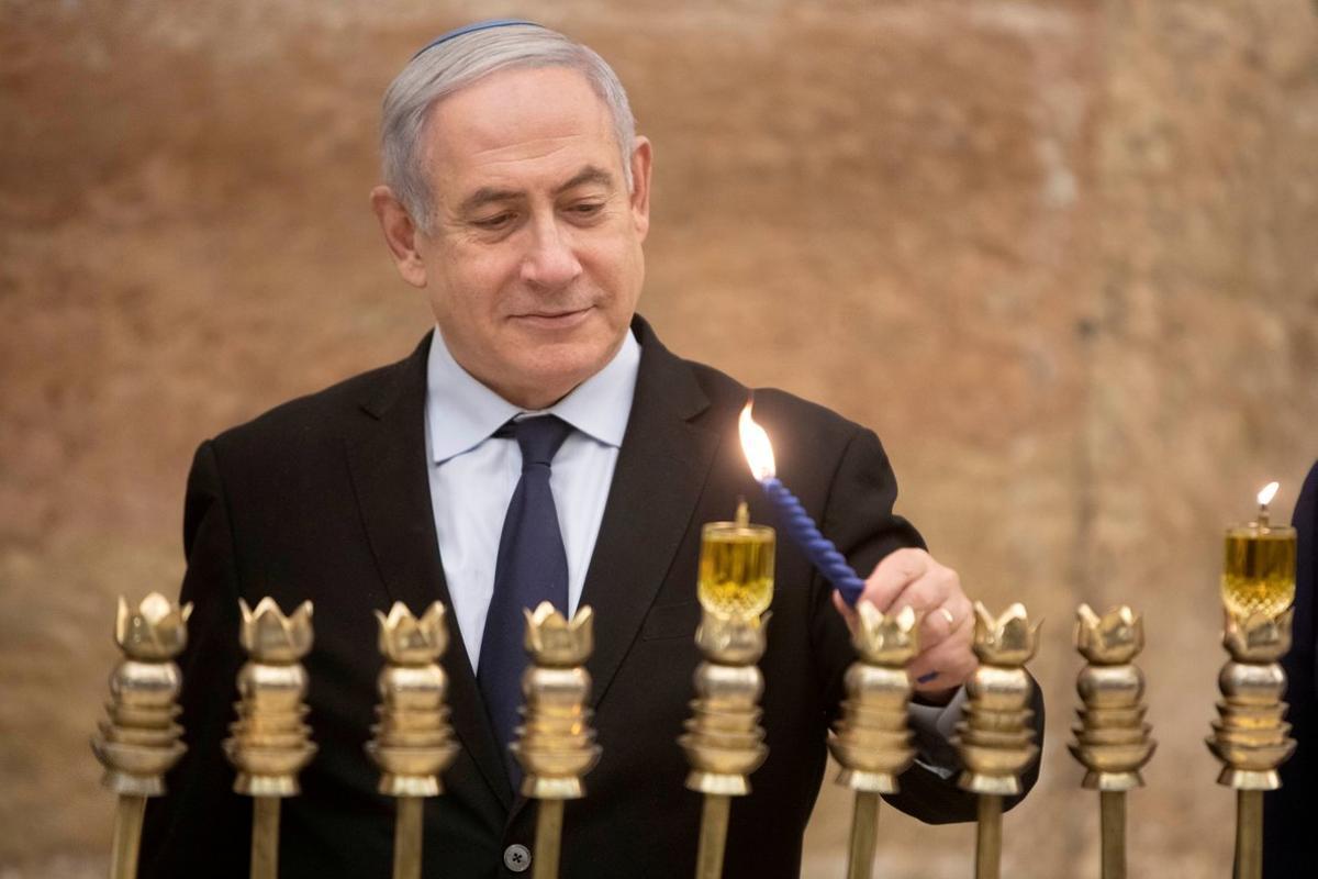 FILE PHOTO: Israeli Prime Minister Benjamin Netanyahu, lights a Hanukkah candle at the Western Wall, the holiest site where Jews can pray in Jerusalem’s old city, December 22, 2019. Sebastian Scheiner/Pool via REUTERS/File Photo