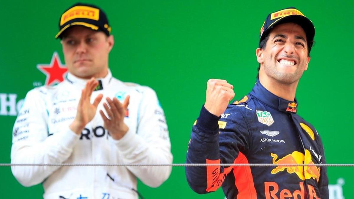 El australiano Daniel Ricciardo (Red Bull) celebra su victoria en China al subir al podio, ante el aplauso de Valtteri Bottas (Mercedes), segundo.