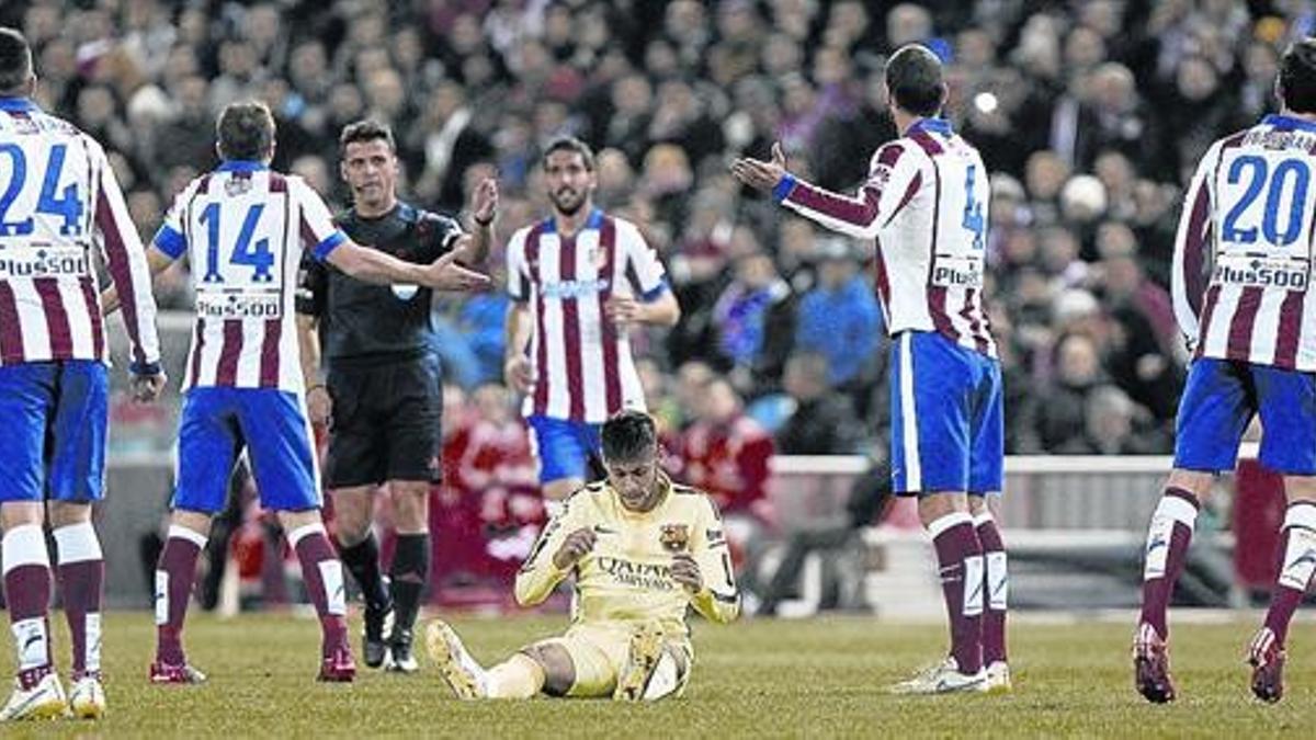 Los jugadores del Atlético protestan una falta, con Neymar en el suelo.