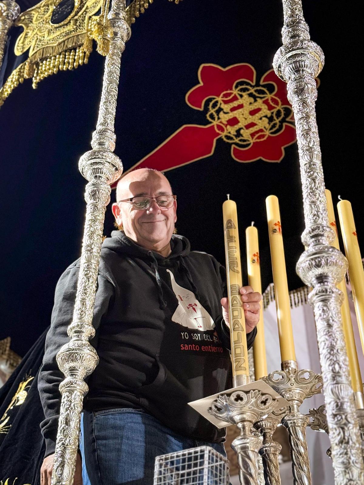 Fernando Sopa, mayordomo prioste de la hermandad del Santo Entierro, coloca la vela de Alcer Badajoz en la candelería de la Virgen de las Lágrimas.