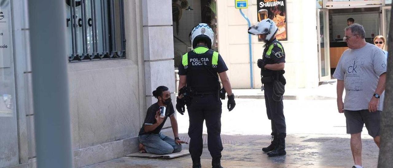 Policías actuando contra una persona que pedía en una céntrica avenida de Alicante, esta semana