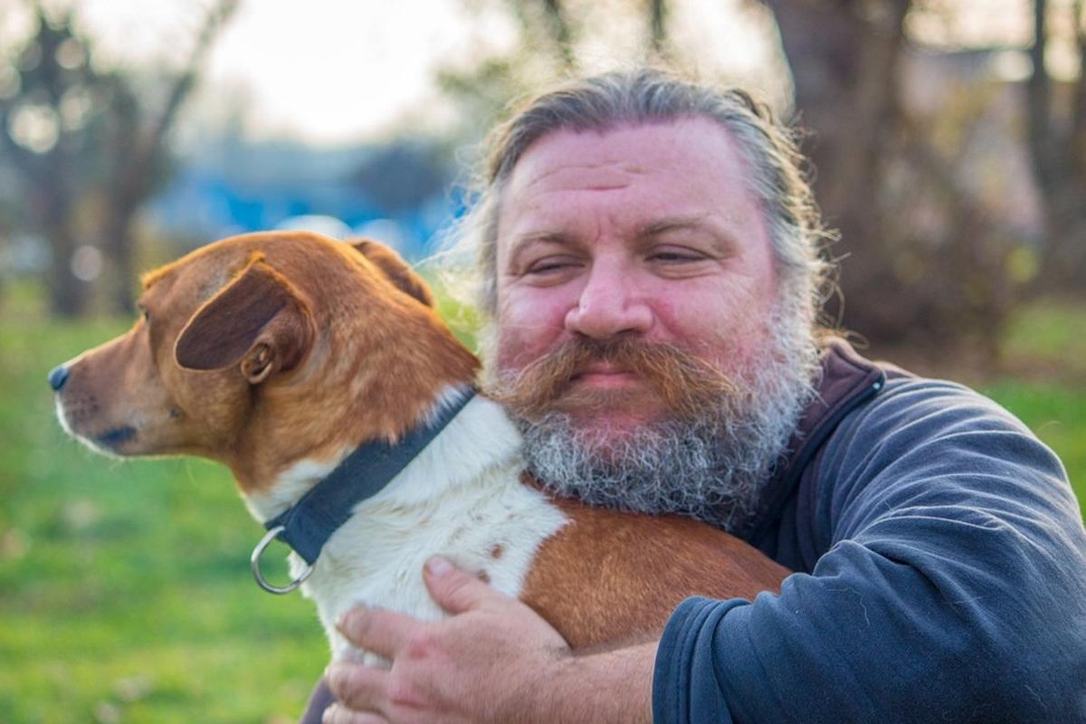 Un hombre con barba junto a su perro.