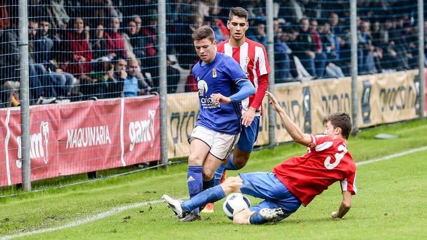 El juvenil del Oviedo Sandoval conduce el balon ante Bertin, en el suelo, y Orellano.