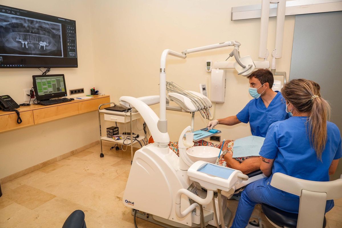 Dos profesionales realizan un tratamiento estético dental en una paciente.