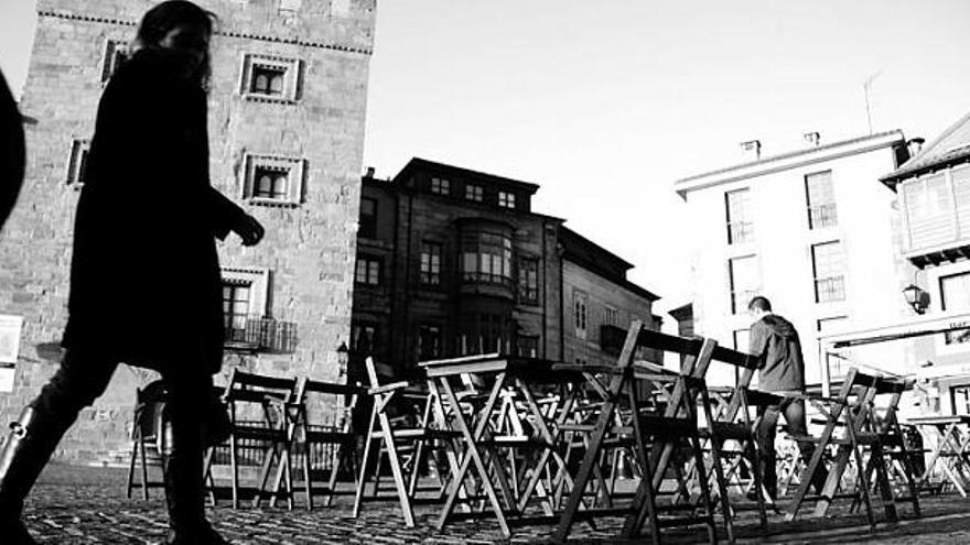 Paseantes ante las mesas y sillas de una terraza en la plaza del Marqués.