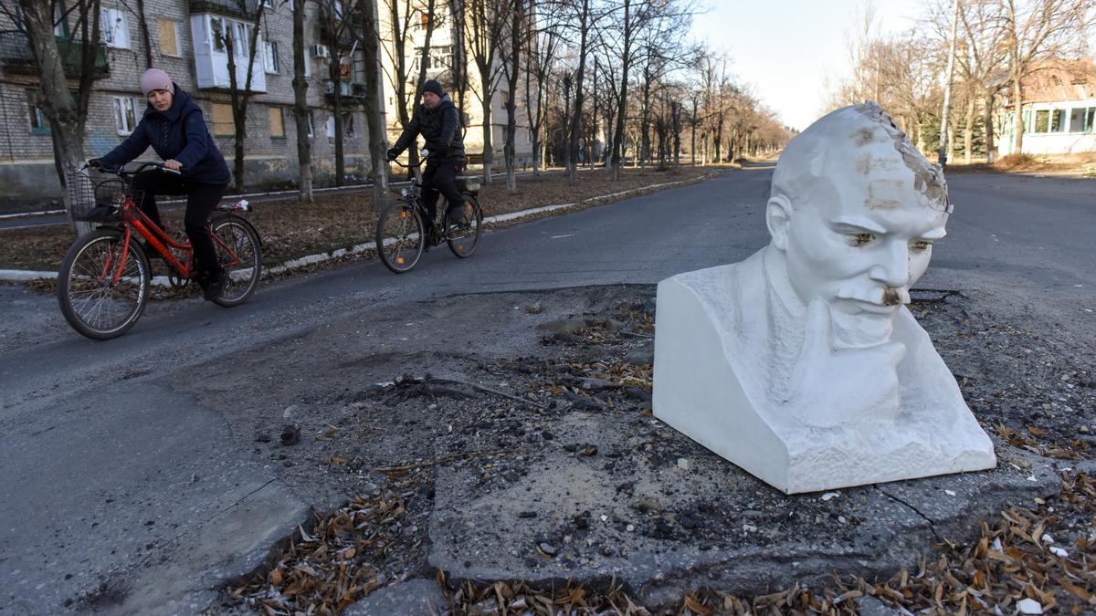 Dos personas pasan junto a un busto de Lenin en la localidad oriental de Bajmut, donde combaten las fuerzas rusas y ucranianas desde hace meses.
