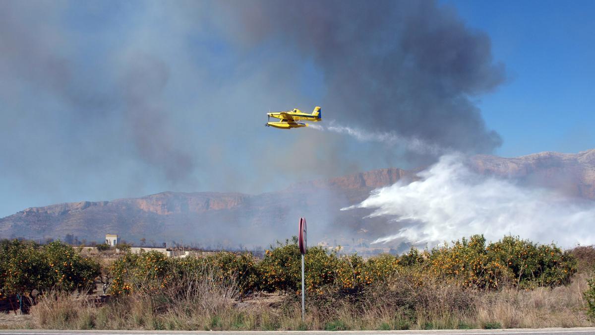 Uno de los medios aéreos que participan en la extinción del incendio de Xàbia descargando agua sobre la zona