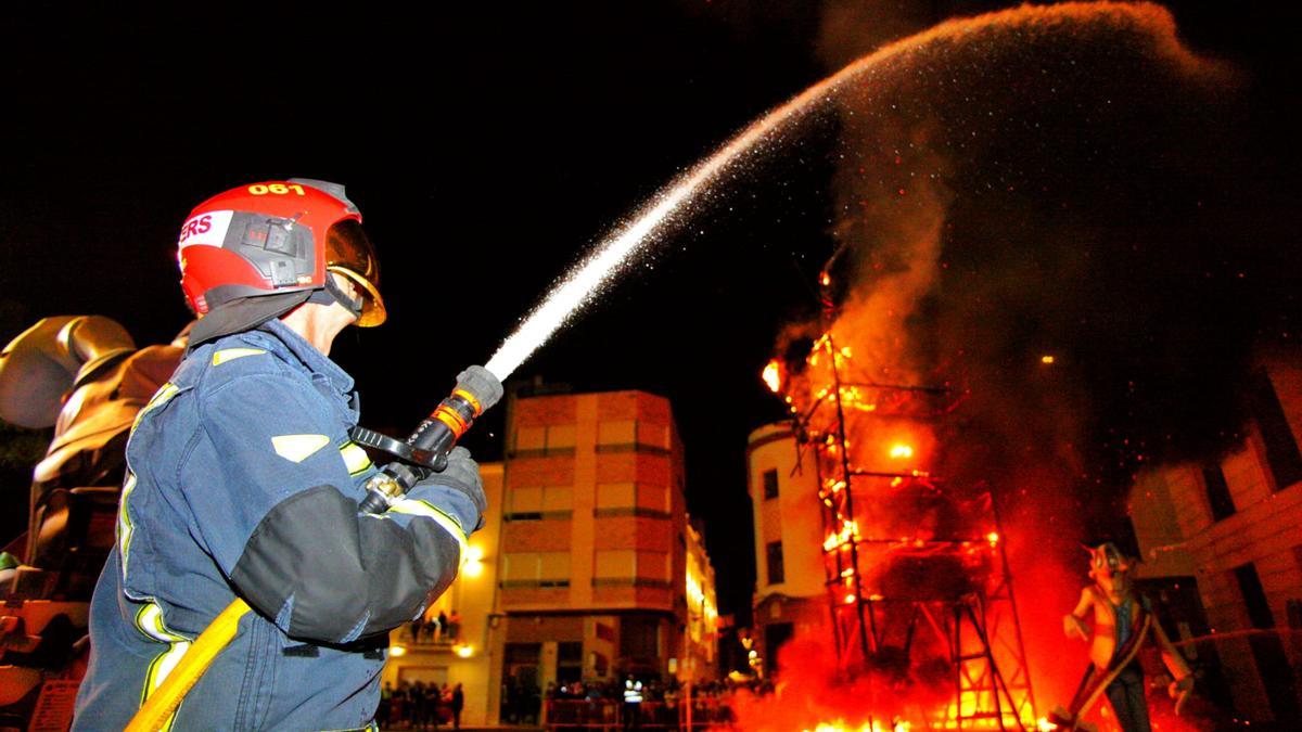 Un bombero tira un chorro de agua a la estructura en llamas de la falla Barri la Vila.