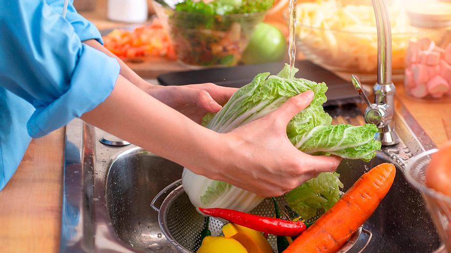 Una persona lavando una lechuga.