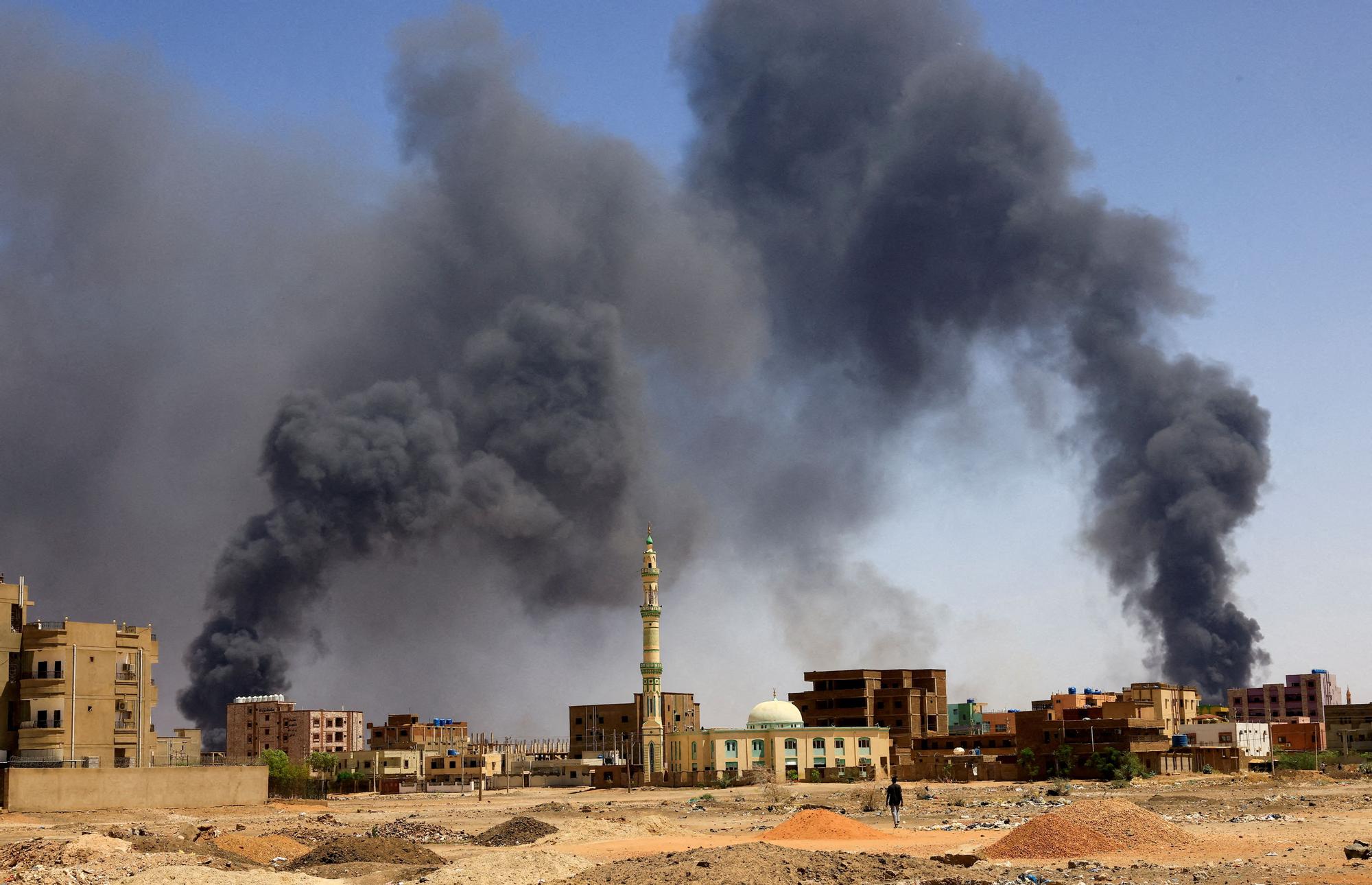 Un hombre camina hacia las columnas de humo provocadas por un bombardeo aéreo después de un bombardeo en Jartum.