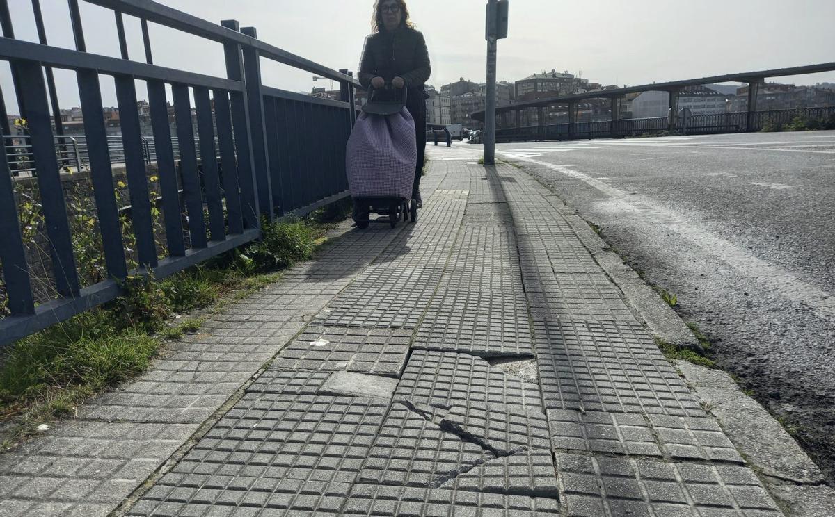 Baldosas sueltas en una acera de acceso al centro comercial en las que esta semana se cayó un vecino.