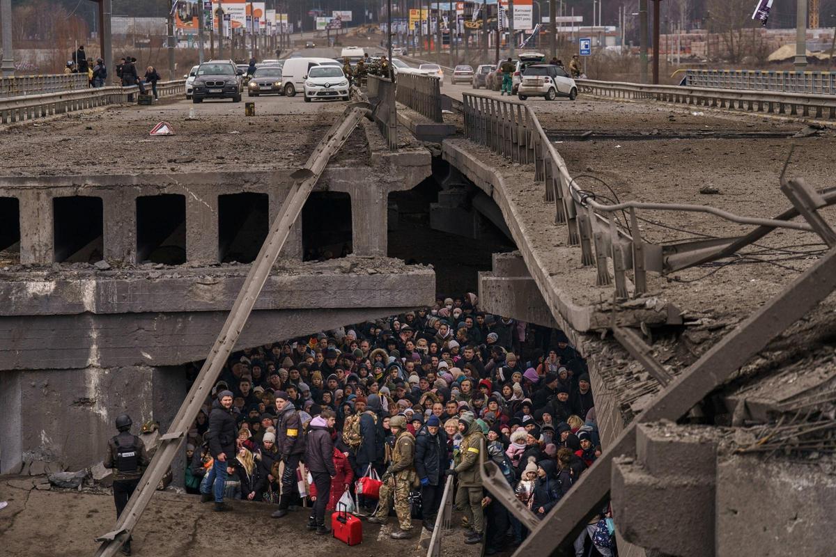 Una multitud debajo de un puente destrozado mientras intentan huir a las afueras de Kiev en Ucrania.