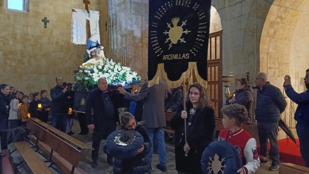 Los niños de comunión y confirmación custodian la imagen de Nuestra Madre de Arcenillas en una procesión contenida en el templo por la lluvia.