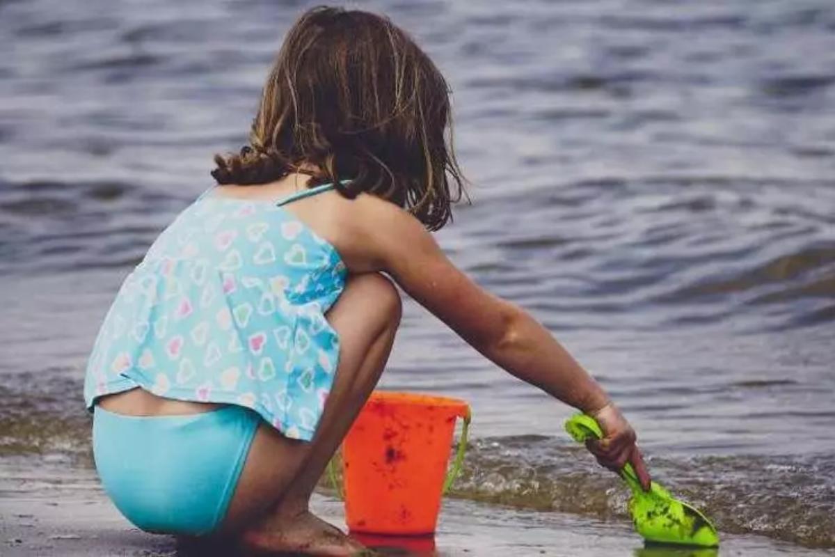 Imagen de archivo de una niña, con un cubo y una pala a la orilla del mar.