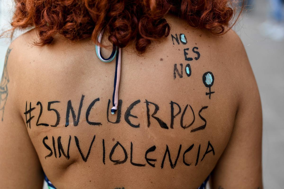 Una activista feminista de espaldas leyendo “No es no. Cuerpos sin violencia ”, participa en una manifestación en el Día Internacional de la Eliminación de la Violencia contra la Mujer en Caracas.