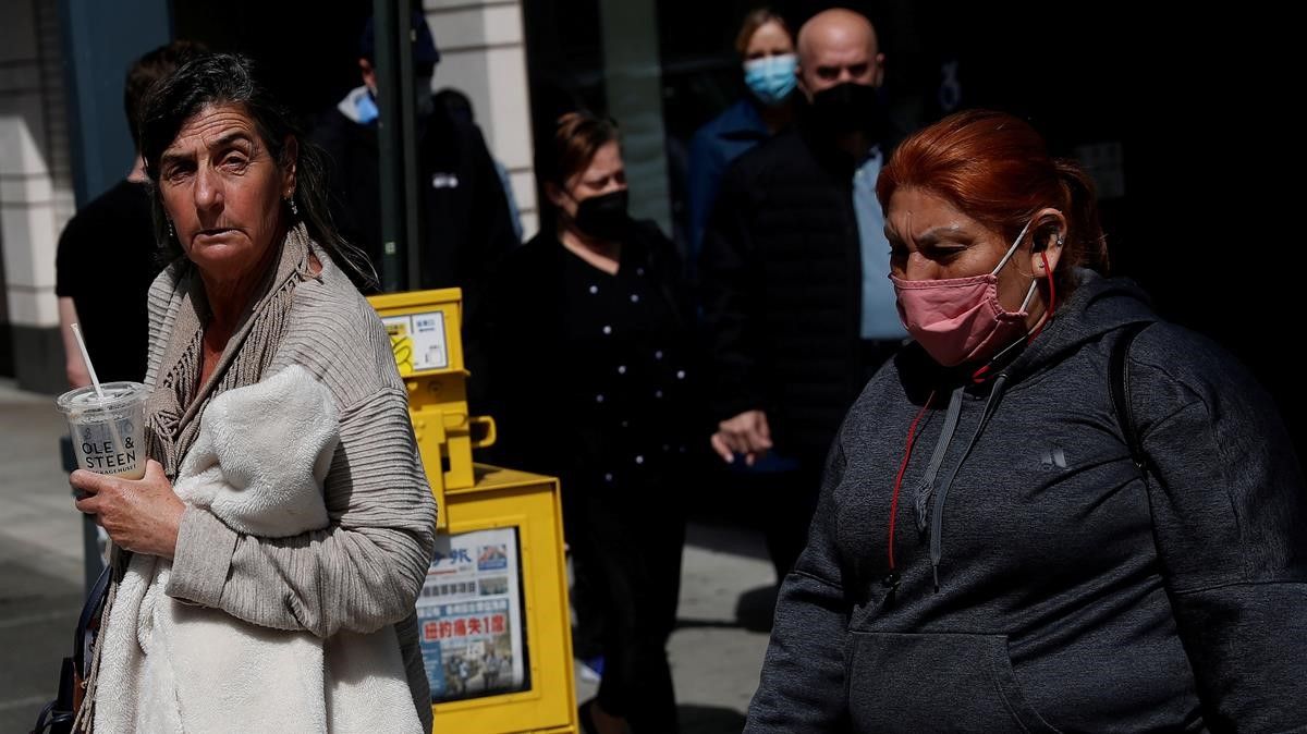 Una mujer camina sin mascarilla por las calles de Manhattan, en la ciudad de Nueva York (EEUU) rodeada de gente que sí la lleva, el pasado 27 de abril