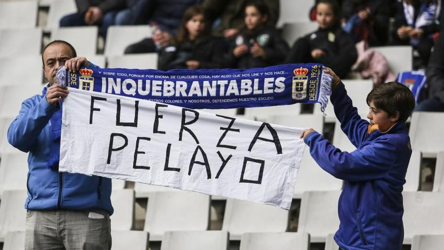 Dos aficionados del Oviedo muestran una pancarta de apoyo a Pelayo Novo antes del partido contra el Alcorcón.