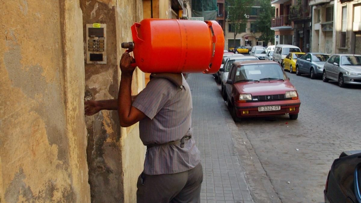 Una persona entra a una casa con una bombona de butano