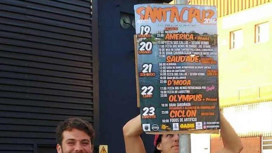 Jóvenes colocando el cartel de las fiestas en una calle de Santa Cruz.