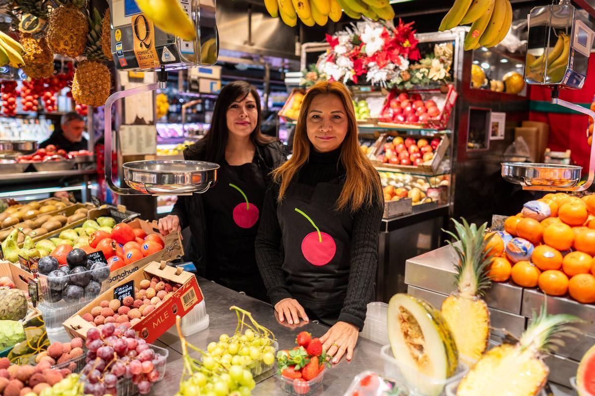 Leonela y Jessica, dependientas de Morilla Fruites, atienden a clientes habituales en una de las paradas históricas del Mercat de la Boqueria