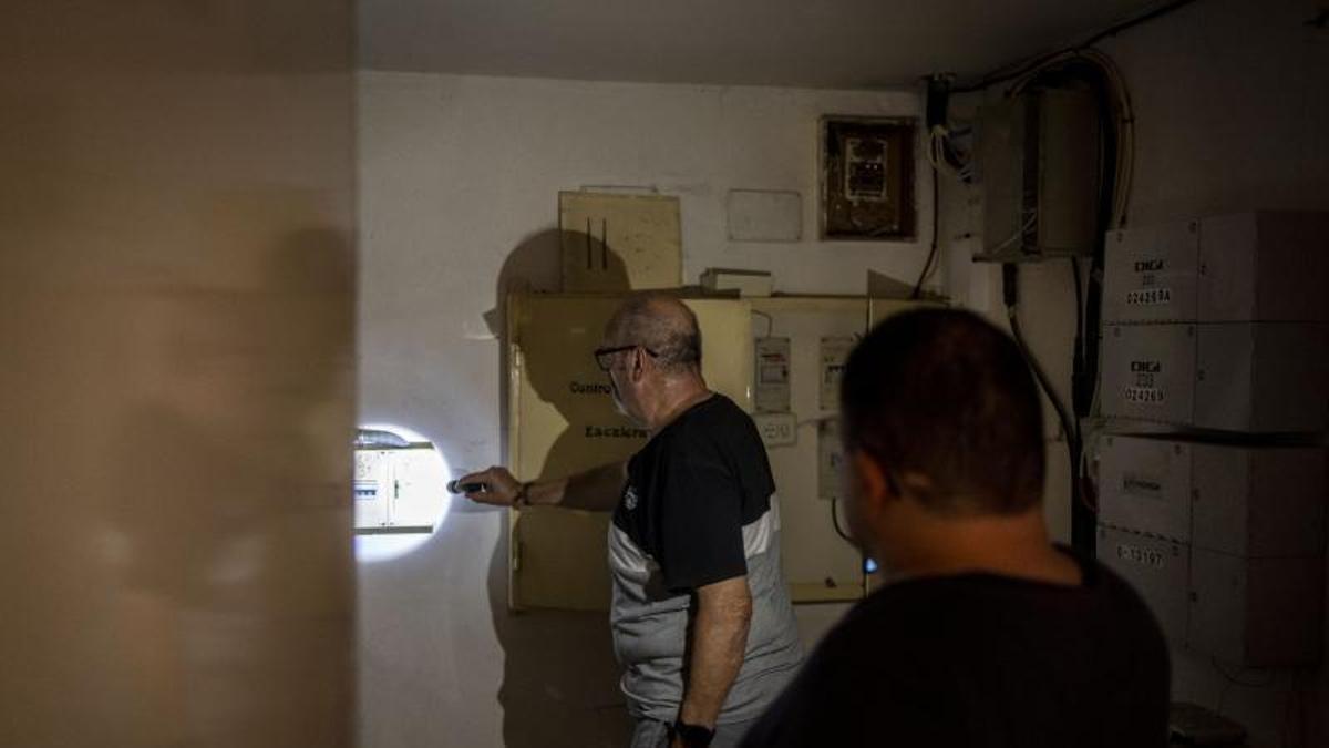 Dos vecinos revisan el contador en el apagón de Zaragoza durante el apagón del lunes.