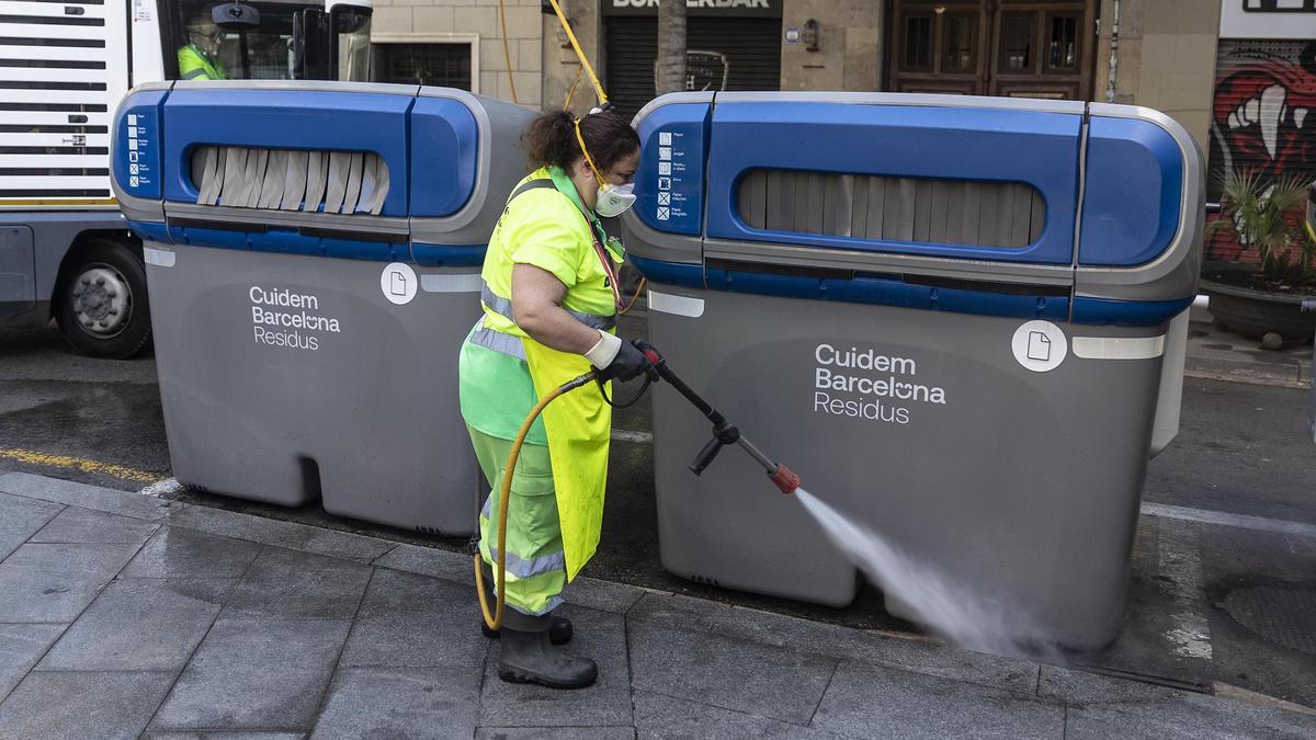 Una trabajadora limpia unos contenedores en Barcelona.