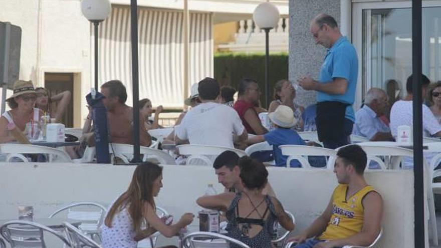 Un camarero atiende mesas en una terraza de la playa de Gandia.