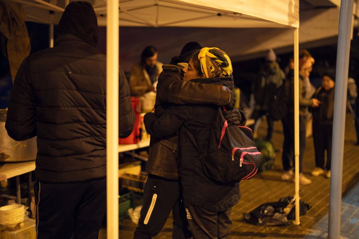 Voluntarios de distintas entidades privadas reparten comida para la cena de Nochebuena bajo la autopista C-31, donde aún duermen decenas de personas desalojadas del antiguo instituto B9
