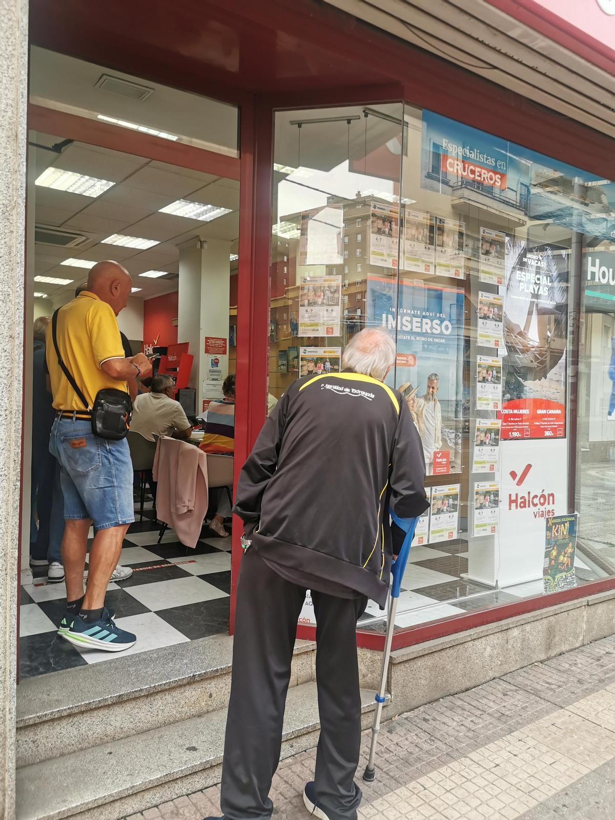 Mayores a las puertas de un agencia de viajes de Cáceres, ayer.