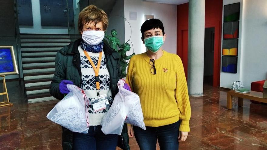 Una voluntaria tras recoger varias bolsas con telas junto a una trabajadora de Rolser