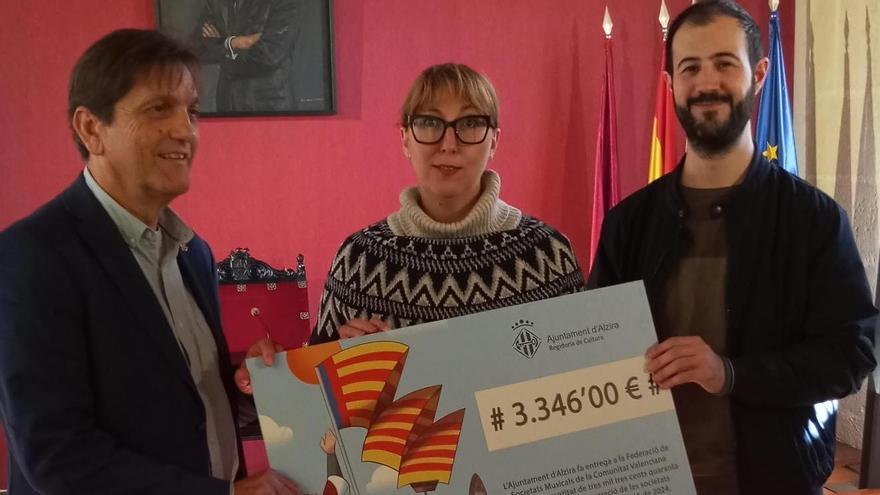 L'alcalde d'Alzira i el regidor de Cultura entreguen el xec a la presidenta de la FSMCV, Daniela González.
