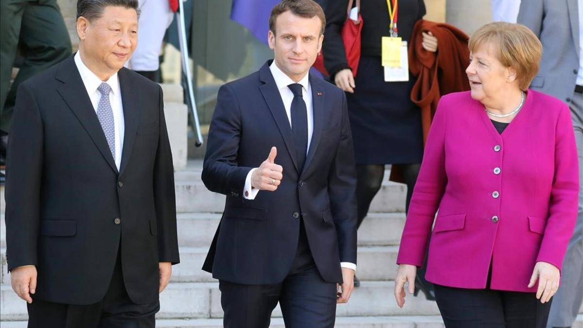 El presidente Emmanuel Macron (centro), flanqueado por la cancillera Angela Merkel (derecha) y el presidente chino Xi Jinping.