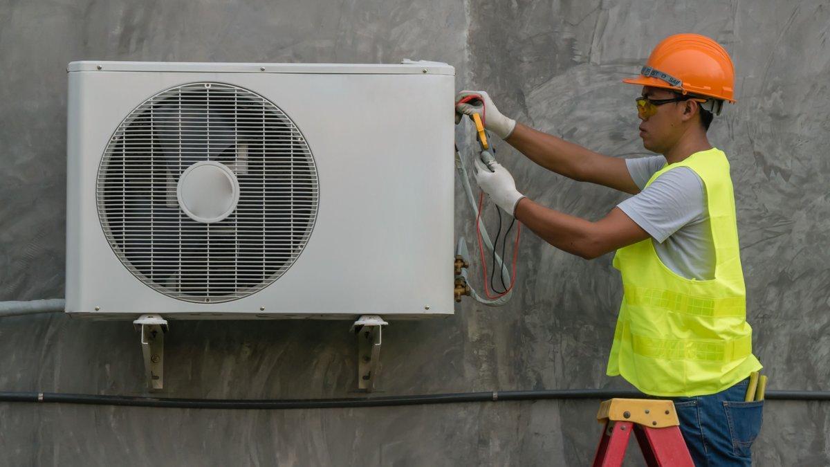 Un técnico revisa un aparato de aire acondicionado.