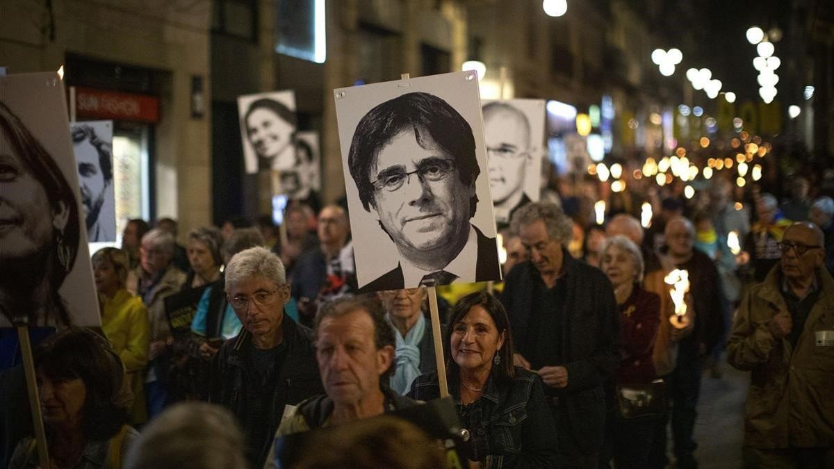 Manifestantes independentistas exhiben carteles con los rostros de Puigdemont y el resto de líderes del 'procés', el pasado octubre, en Barcelona.