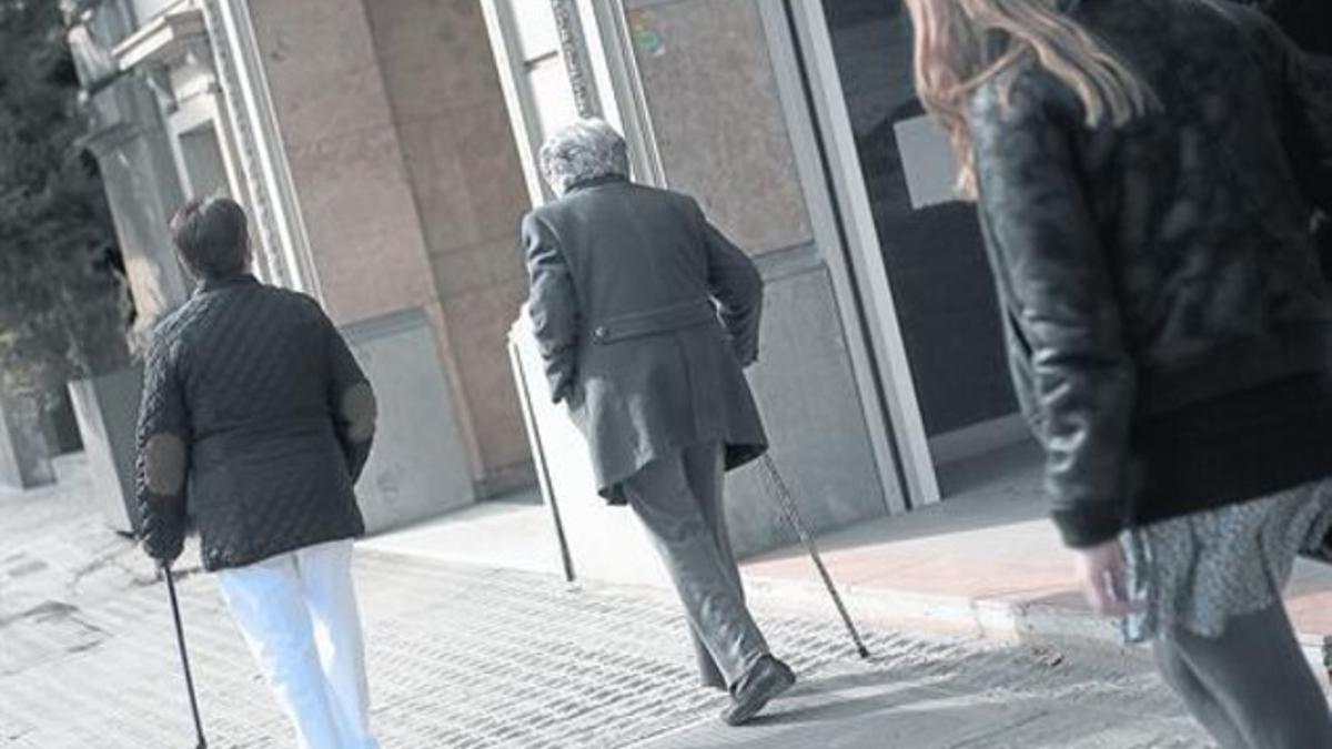 Una anciana y su cuidadora andan por una calle de Barcelona, el viernes.