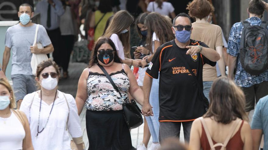 Varias personas caminan con mascarilla en Valencia.
