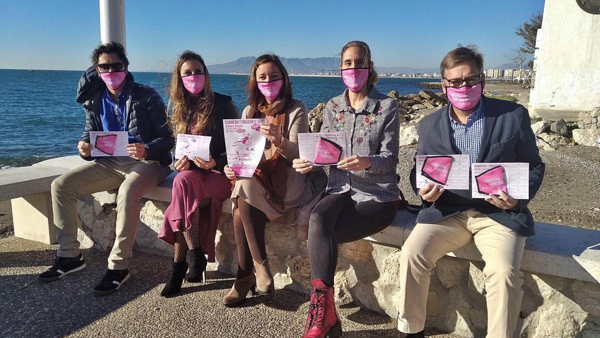Representantes de algunos de los colectivos que luchan contra el cáncer en Málaga y mejoran la vida de pacientes y familiares posan con carteles de la VIII edición de la Carrera por las Mujeres contra el Cáncer.