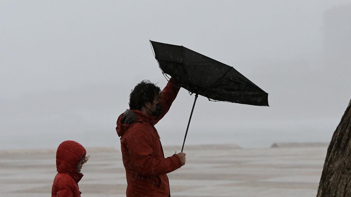 Dos personas caminan por la zona de las Esclavas, en A Coruña (Galicia), durante el temporal con fuertes rachas de viento que ha provocado la borrasca Barra