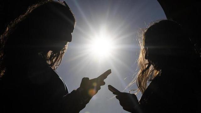 Dos adolescents, amb els seus mòbils.