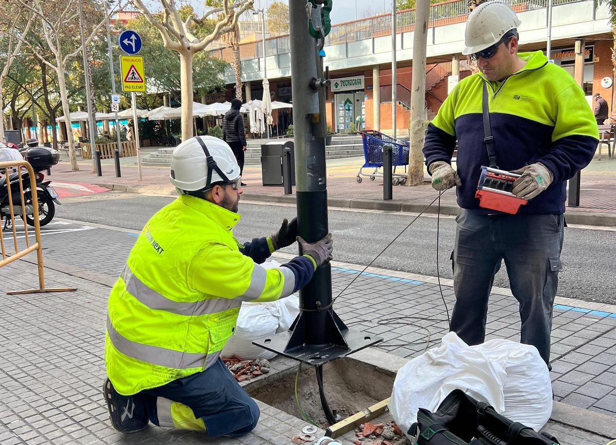 Dos operarios retiran una farola en Esplugues de Llobregat