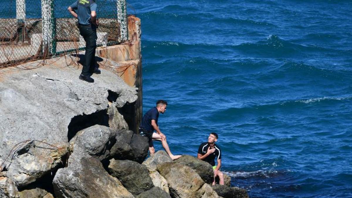 Unos guardias civiles atienden a un marroquí que llegó este lunes a nado a Ceuta.
