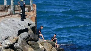 Unos guardias civiles atienden a un marroquí que llegó este lunes a nado a Ceuta.