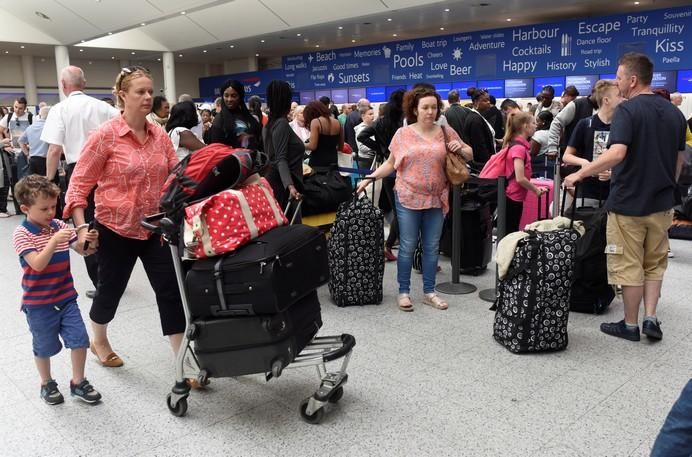 People queue with their luggage for the British ...