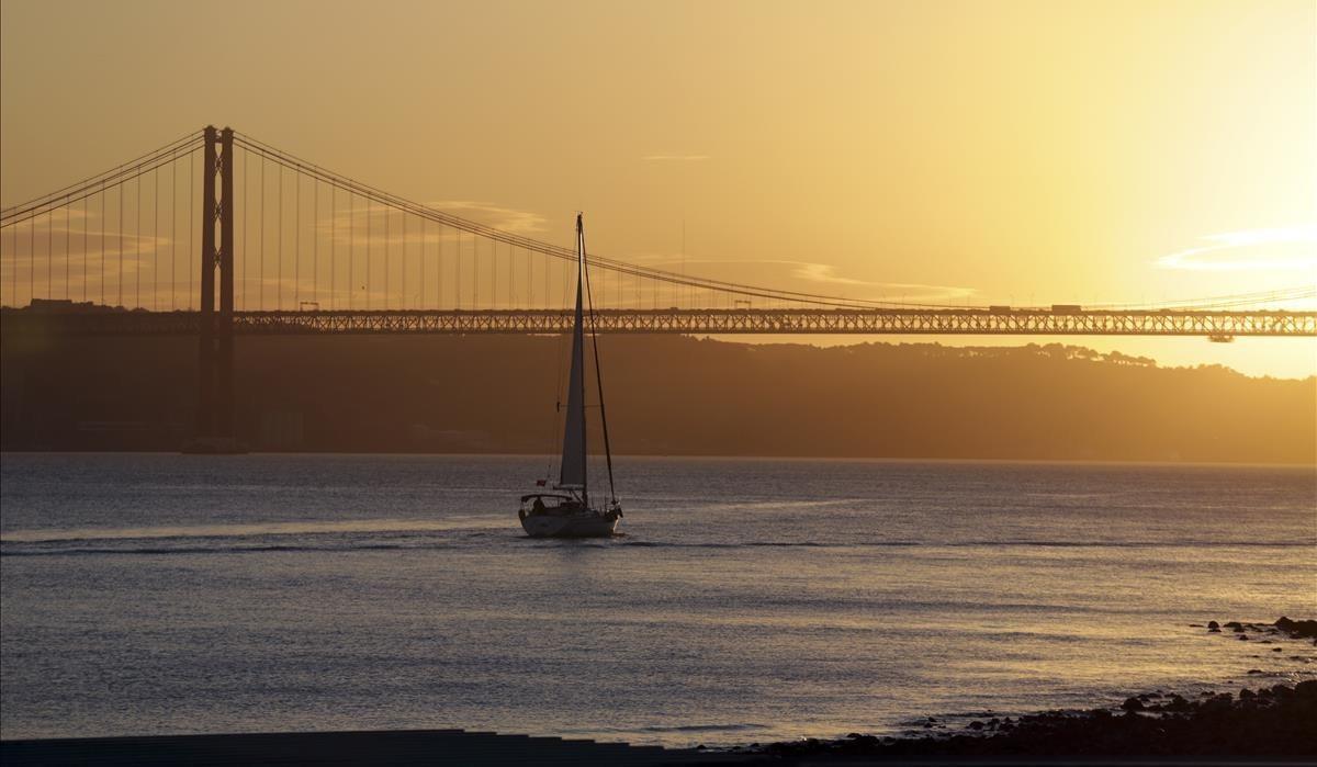 lainz41809002 a boat sails down the tagus river towards the april 25th bri180204115927