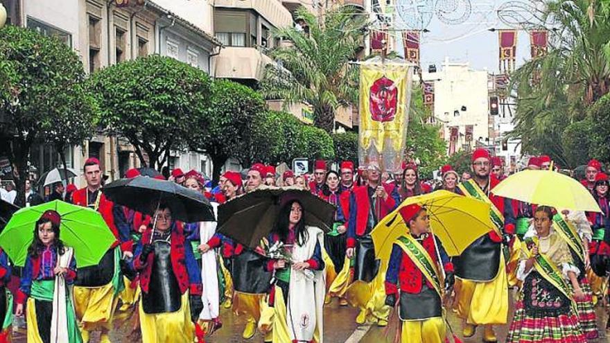 Los cargos festeros encabezan el desfile con paraguas.